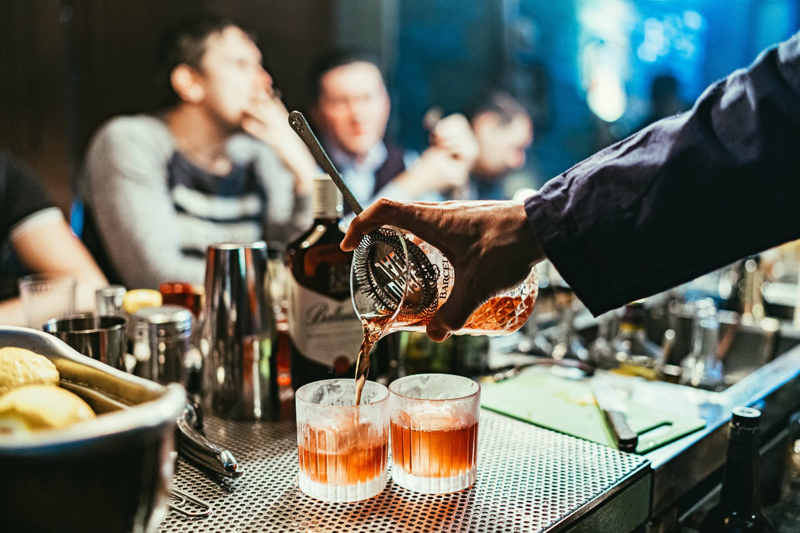 Photo of friends sitting at a bar in front of a barman making cocktails